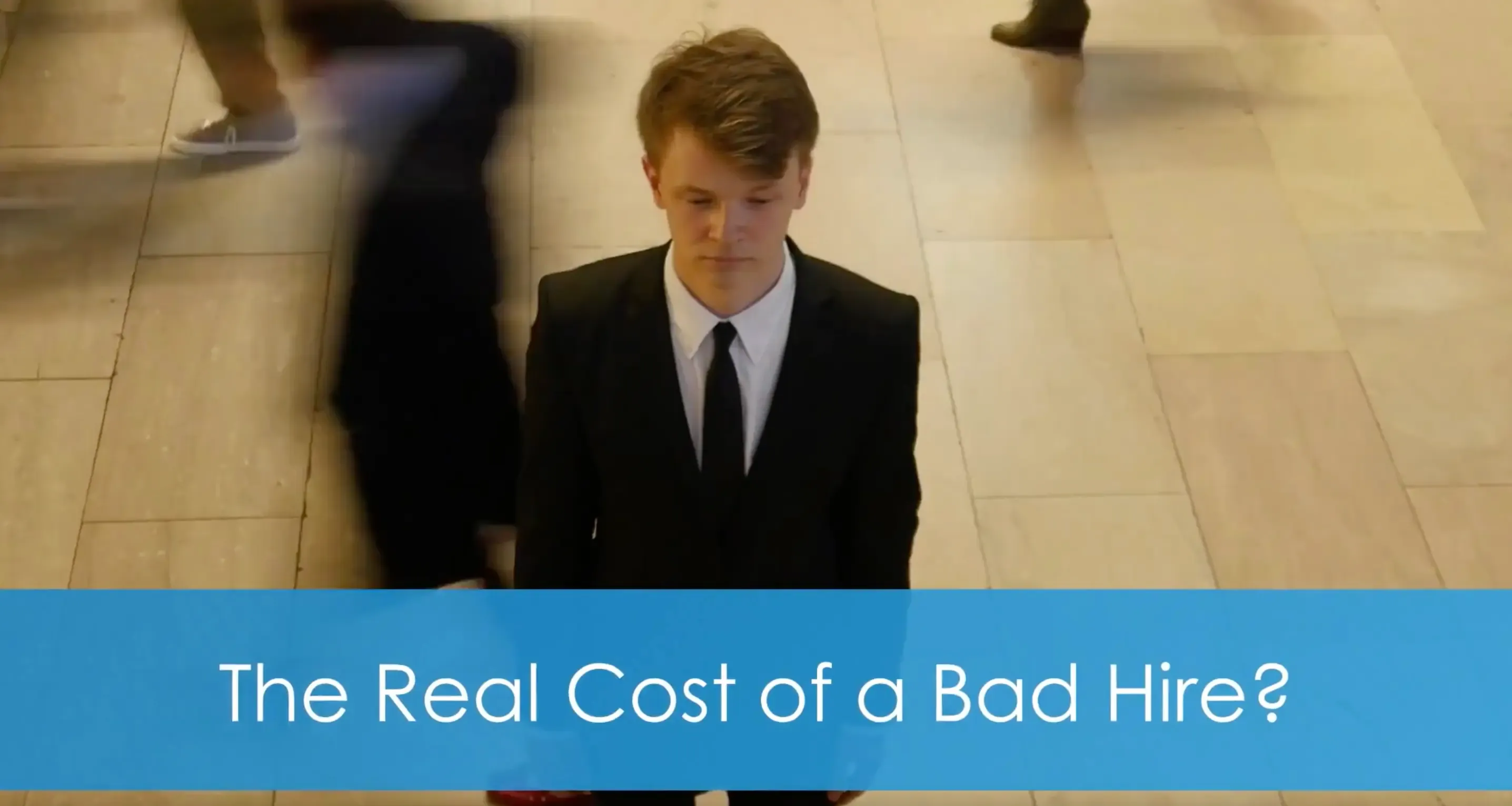 A job candidate in a suit standing still in a busy office corridor while others walk past