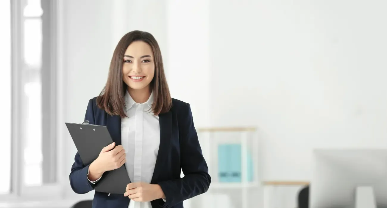 A legal professional in a dark suit holding a clipboard in a bright office